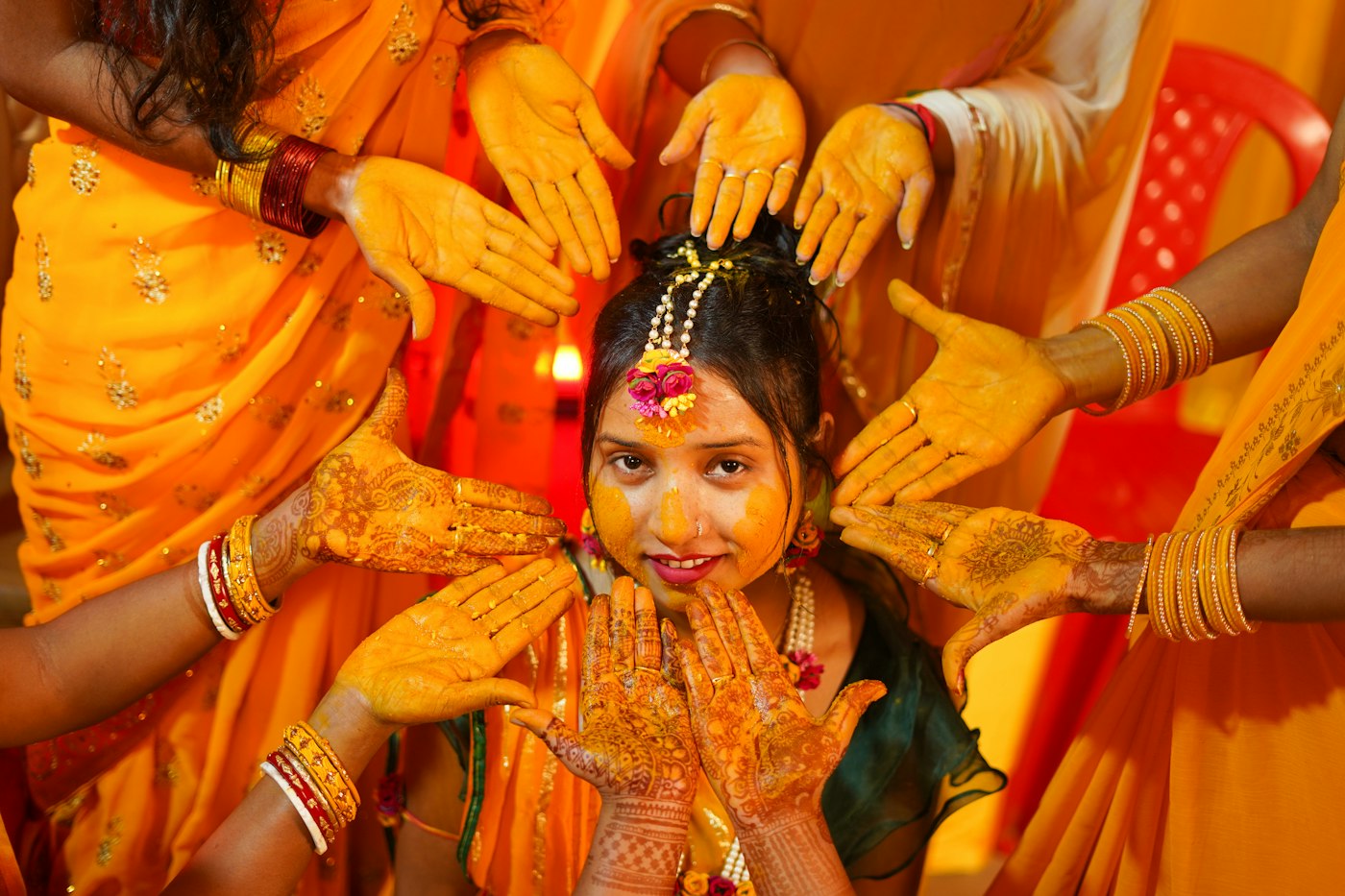 Bride laughing as hands smear haldi on her